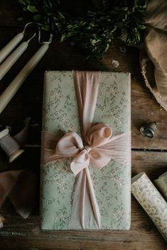 a wrapped present sitting on top of a wooden table next to candles and other items