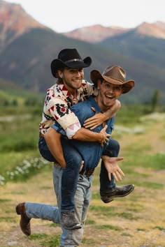 two men in cowboy hats are carrying each other on their shoulders and smiling at the camera