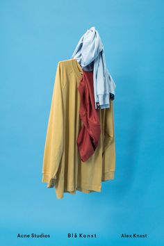 two shirts hanging on a clothes line against a blue background with one shirt folded over the other