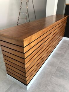 a large wooden counter sitting on top of a tile floor next to a ladder in a room