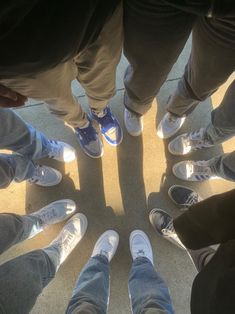 a group of people standing in a circle with their feet up on the ground looking down at them