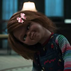 a creepy doll with red hair and pink flowers in her hair is looking at the camera