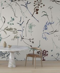 a white table and chair sitting in front of a wall with flowers painted on it