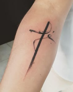 a cross tattoo on the left arm and forearm is shown in black ink with an artistic design