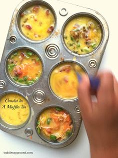 a muffin tin filled with lots of different types of food in it and someone holding a blue marker