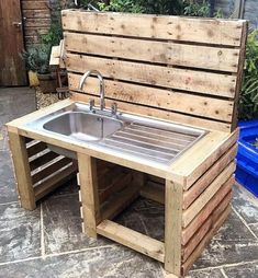 an outdoor sink made out of wooden pallets with a blue trash can in the background