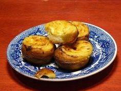 small pastries on a blue and white plate sitting on a red tablecloth with a wooden surface