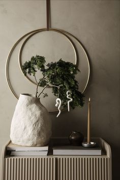 a white vase sitting on top of a table next to a candle and some books