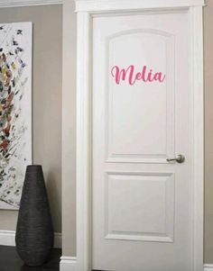 a white door with the word mela painted on it next to a black vase