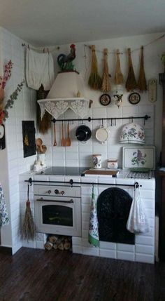 an old fashioned kitchen with white appliances and wooden floors, decorated with hanging pots and pans