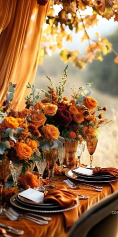 the table is set with orange flowers and place settings