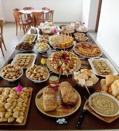 a table filled with lots of different types of food on plates and serving utensils