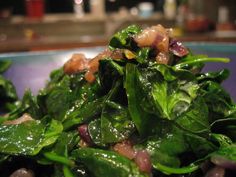 spinach salad with onions and dressing in a blue bowl