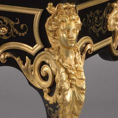 an ornate gold and black table with a woman's head on it