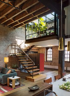 a living room filled with furniture and a spiral staircase in front of a brick wall