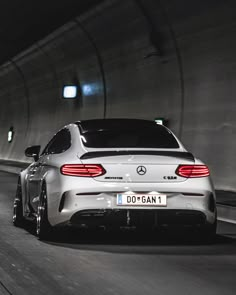 the rear end of a white car driving through a tunnel