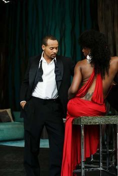 a man in a tuxedo standing next to a woman in a red dress