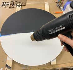 a person using a power drill to paint a white circle