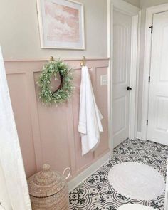 a bathroom with pink walls, black and white flooring and a wreath on the wall