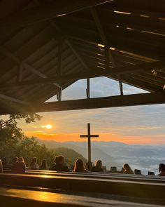 people are sitting in pews at sunset with the sun setting over mountains behind them