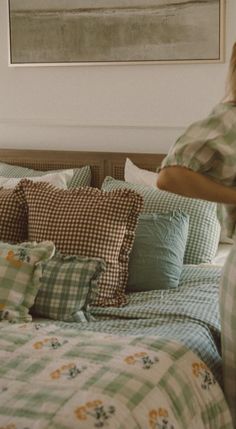 a woman standing in front of a bed with pillows