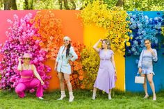 three women are standing in front of colorful flowers