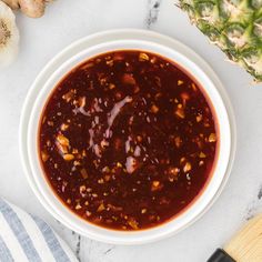 a white bowl filled with chili sauce next to some pineapples and other ingredients