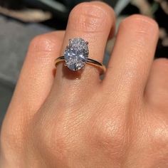 a woman's hand holding a ring with a diamond in the middle and an engagement band around it