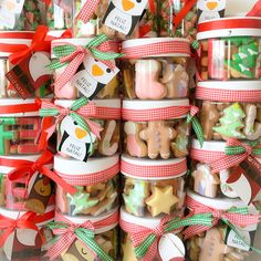 a stack of christmas cookies in glass jars with ribbons and tags on them for sale