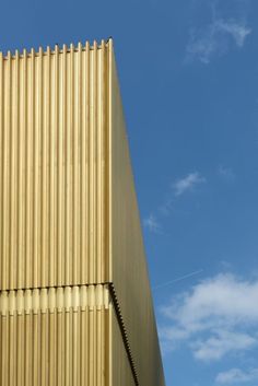 the side of a tall building with a clock on it's face and sky in the background