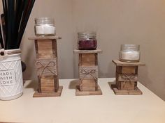 three wooden candles are sitting on a table next to a white vase and candle holder