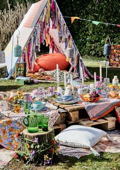 an outdoor picnic with food and drinks on the table, next to a teepee tent