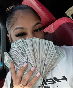 a woman holding money in her hand while sitting in the back seat of a car