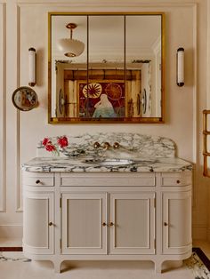 a bathroom with marble counter top and white cabinetry, mirror above the vanity area