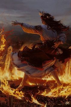 a woman riding on the back of a horse over a fire