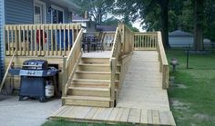 a wooden deck with stairs and grill in the back yard