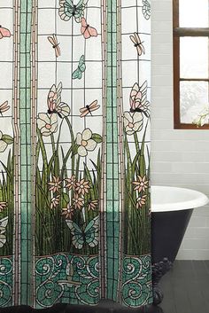 a bath tub sitting next to a shower curtain with flowers and dragonflies on it