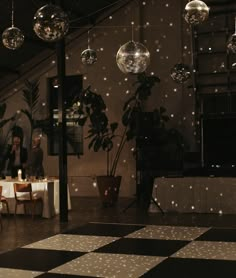 people are sitting at tables in the middle of a room with disco balls hanging from the ceiling