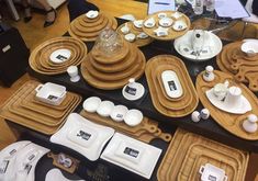 a table topped with lots of wooden plates and bowls filled with teacups, cups and saucers