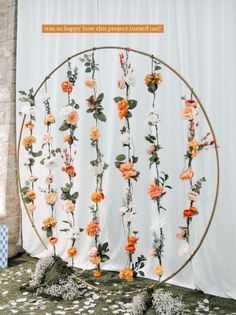 an arrangement of flowers is arranged in a circle on the floor next to a white curtain