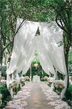 an outdoor wedding ceremony with white drapes and flowers