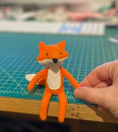 a person holding a small stuffed animal on top of a table