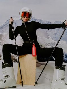 a woman sitting on top of a snowboard with skis and poles in her hands