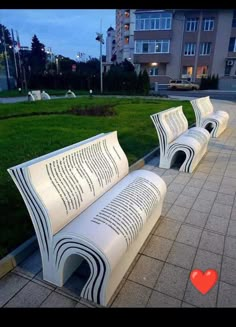 two white benches sitting next to each other on a sidewalk