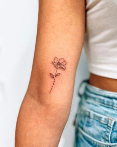 a woman's arm with a single flower tattoo on the left side of her arm