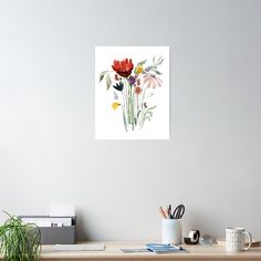 a painting of flowers on a white wall above a desk with office supplies and books