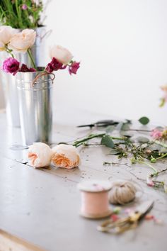 flowers in a vase on a table next to thread and scissors