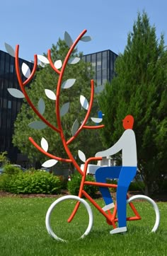 a sculpture of a man on a bicycle with leaves in the shape of a tree