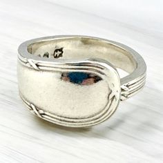 a silver ring sitting on top of a wooden table next to a white surface with a blue stone in the middle