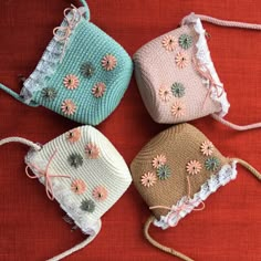 three crocheted purses with flowers on them sitting on a red cloth surface